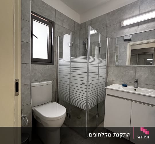 חדר אמבטיה עם מקלחון, כיור ואסלה